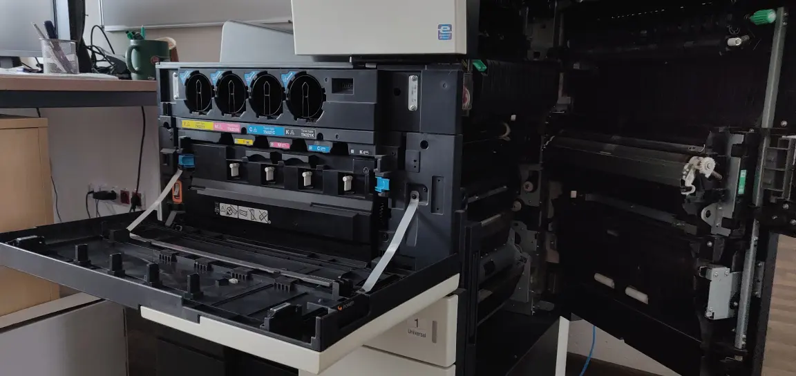 Otwarta drukarka biurowa z widocznymi modułami tonerów i mechanizmem podawania papieru