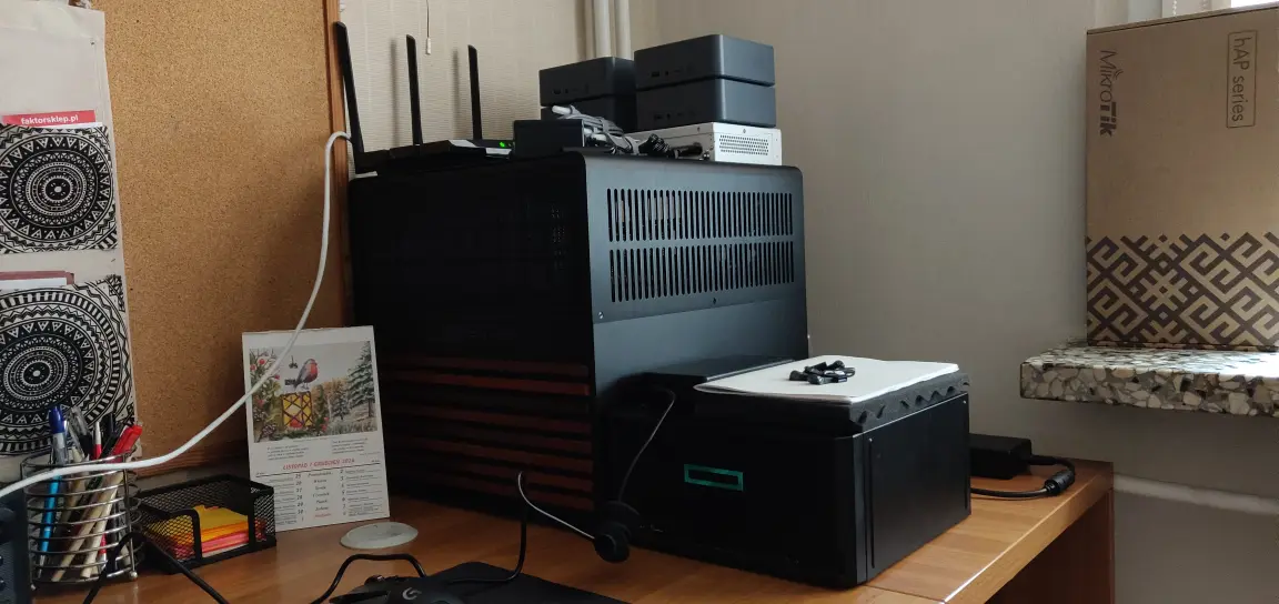 Stanowisko pracy z serwerem, routerami MikroTik i sprzętem sieciowym na biurku